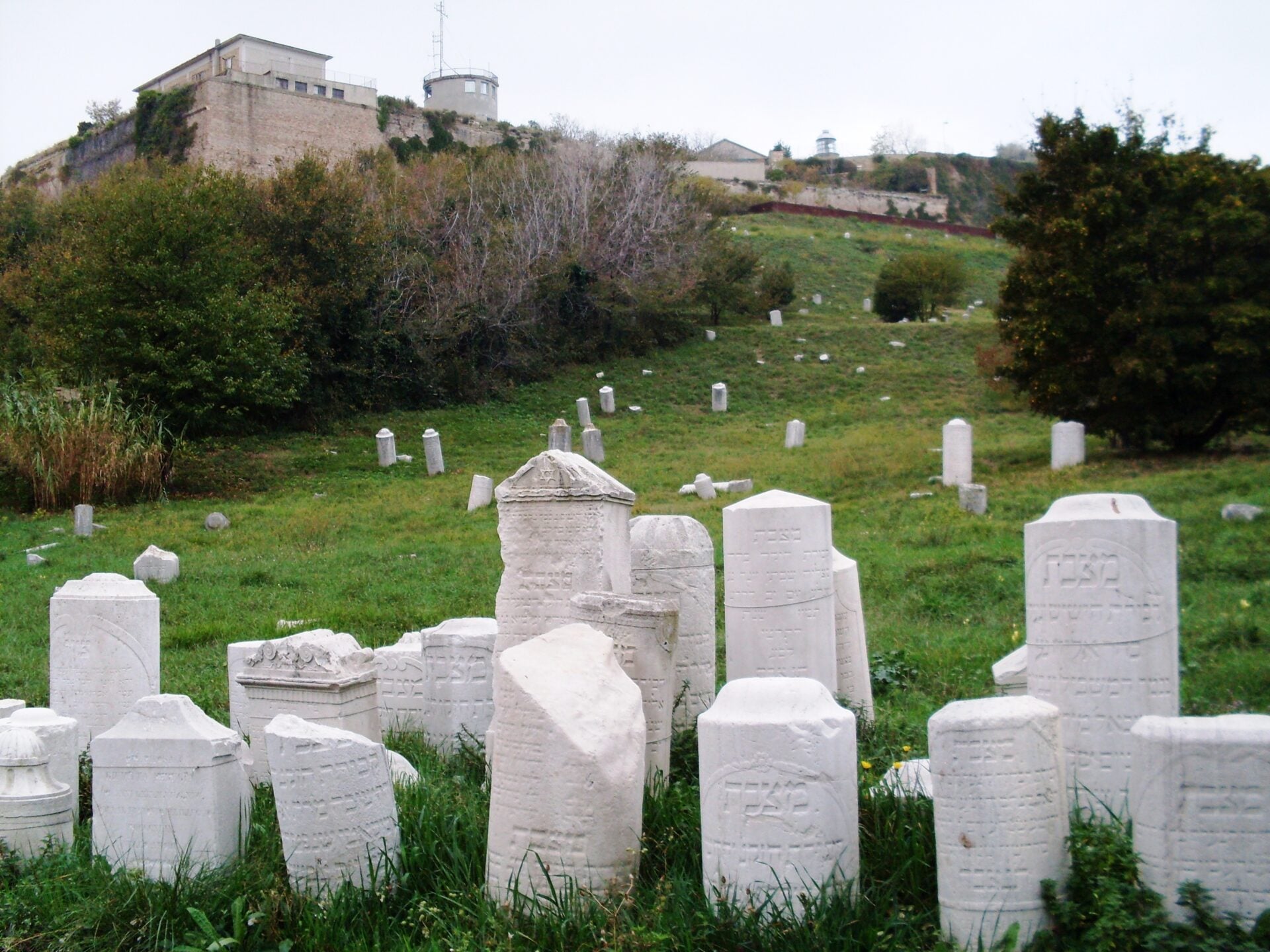 Old cemetery with stone gravestones on grassy hill.