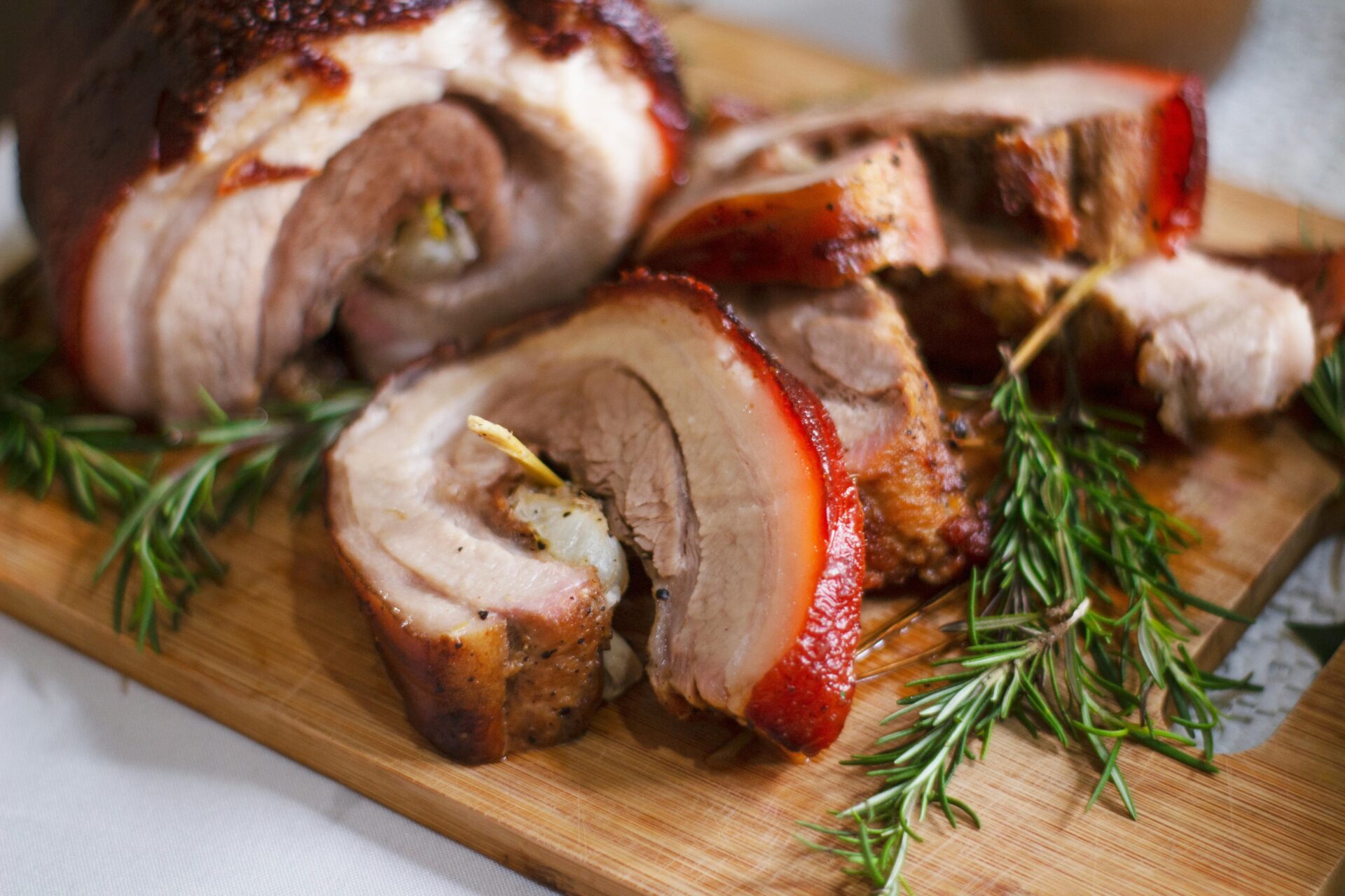 Sliced porchetta with rosemary on wooden board