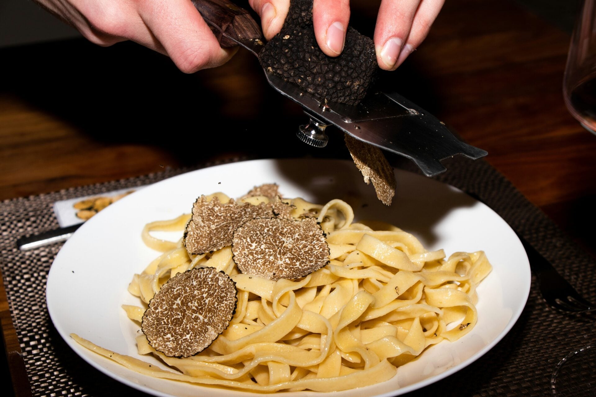 Truffle shavings on pasta in white bowl.